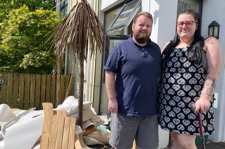 Adam Peterson and Lauryn Mathews with flood-damaged carpets outside their home. 